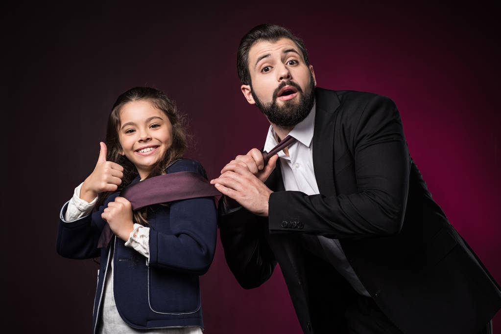 дочь показывает большой палец вверх и тянет отца галстук на бордовый
 - Фото, изображение