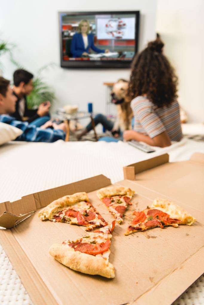 friends watching news with pizza on foreground - Photo, Image