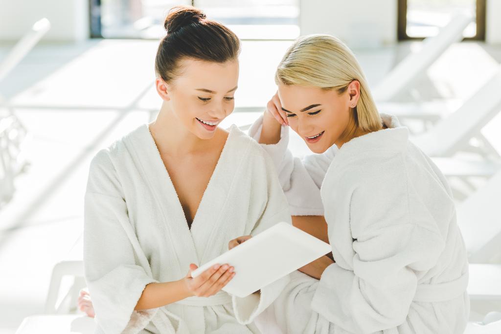 mujeres jóvenes atractivas utilizando tableta en el centro de spa
 - Foto, Imagen