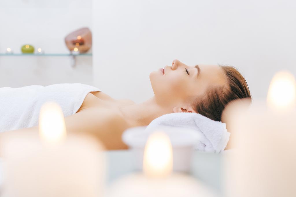 mooie vrouw ontspannen op massagetafel op spa salon - Foto, afbeelding