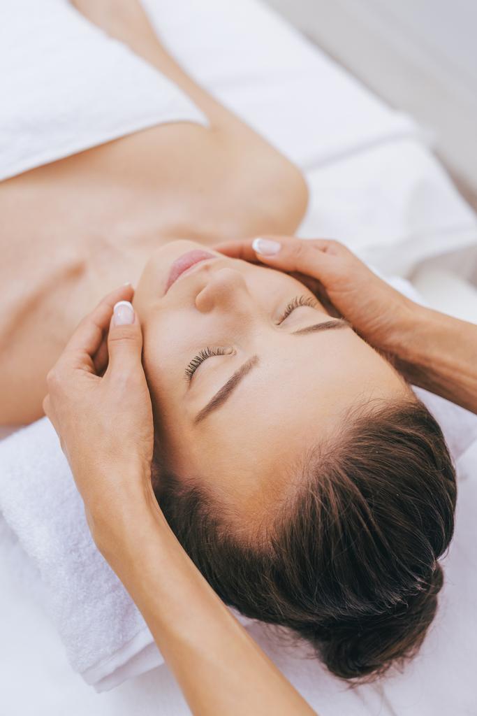 relaxed young woman getting facial massage at spa salon - Photo, Image