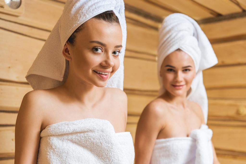 attractive young women covered with towels relxing in sauna and looking at camera - Photo, Image