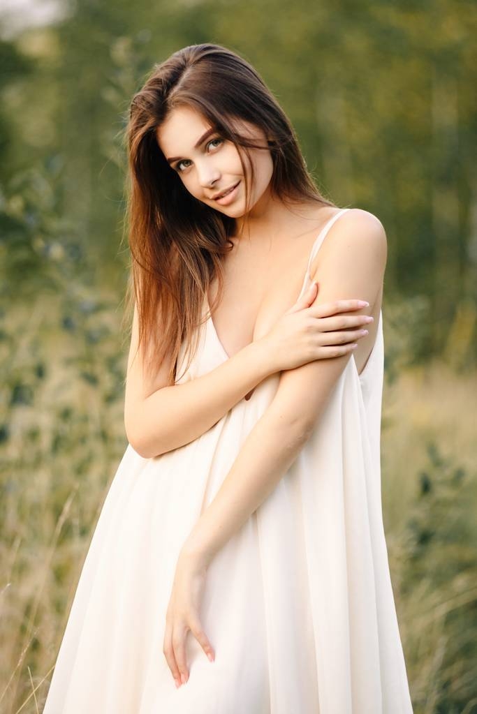 Jovem mulher de vestido branco longo posando na natureza
 - Foto, Imagem