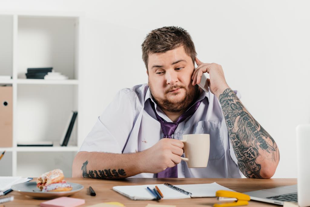 uomo d'affari tatuato in sovrappeso che parla sullo smartphone sul posto di lavoro
 - Foto, immagini