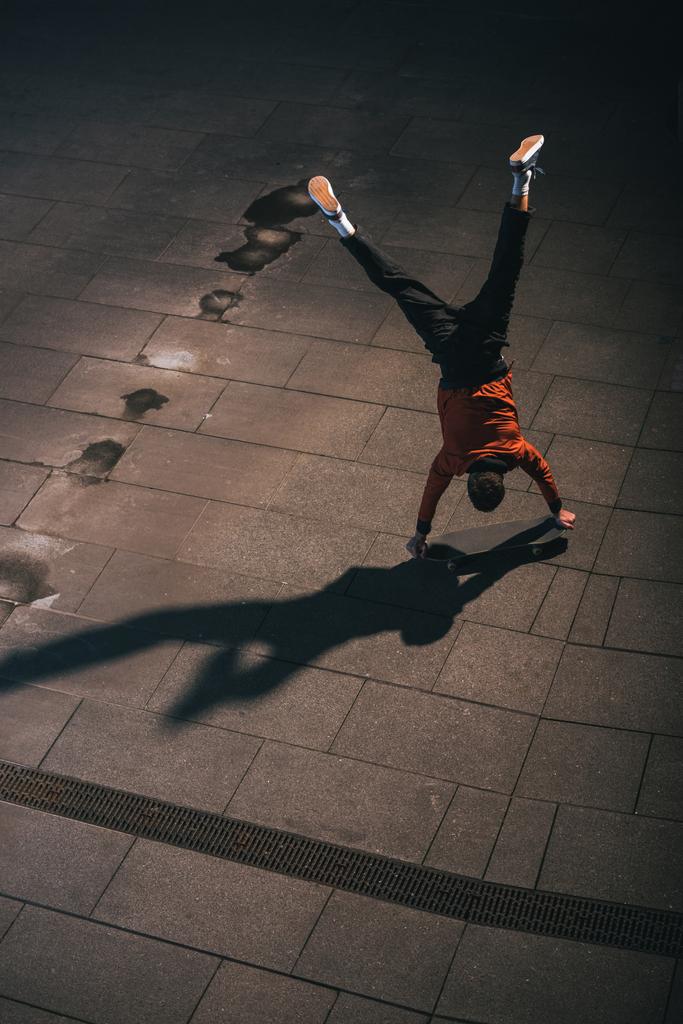 visão de alto ângulo do skatista andando de cabeça para baixo em mãos
 - Foto, Imagem