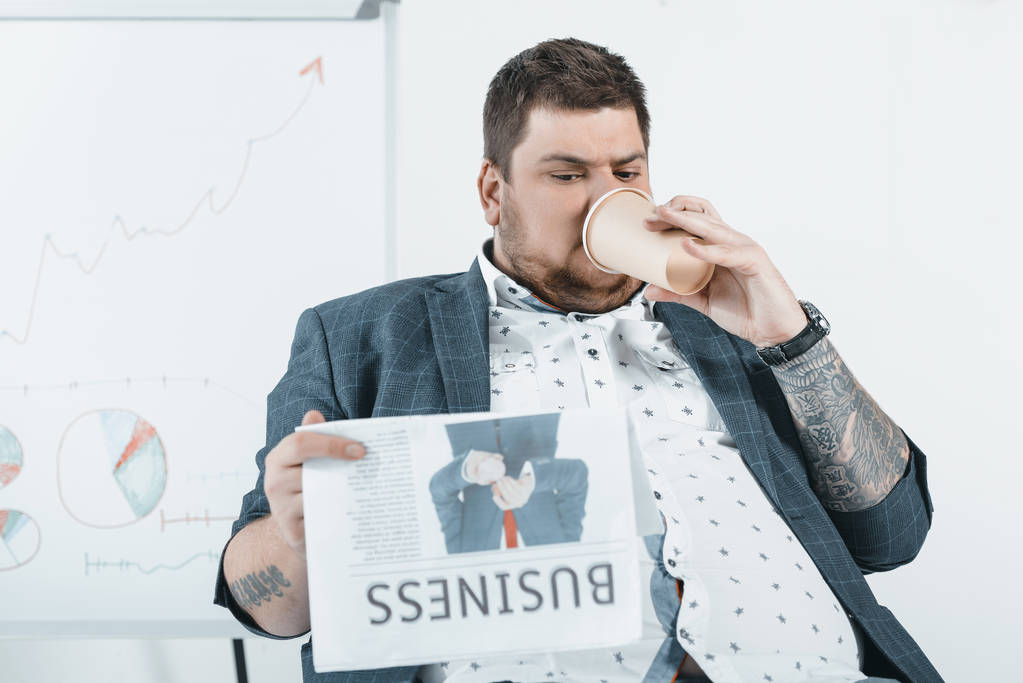 fat businessman drinking coffee and reading business newspaper in office - Photo, Image
