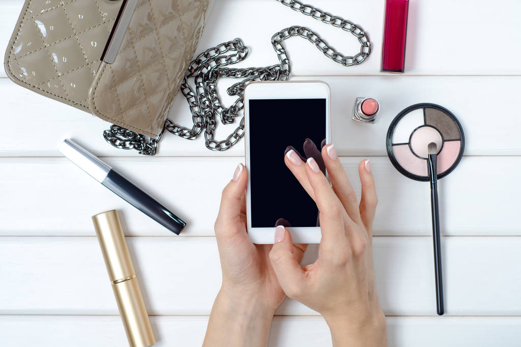 Mano femminile in possesso di uno smartphone cellulare cosmetico borsa
 - Foto, immagini