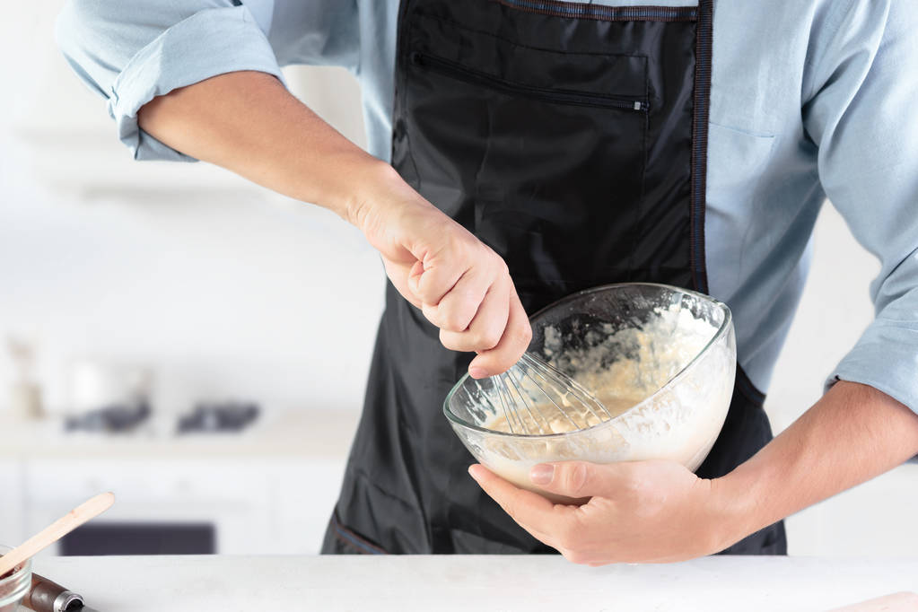 Um cozinheiro com ovos em uma cozinha rústica contra o fundo das mãos dos homens
 - Foto, Imagem
