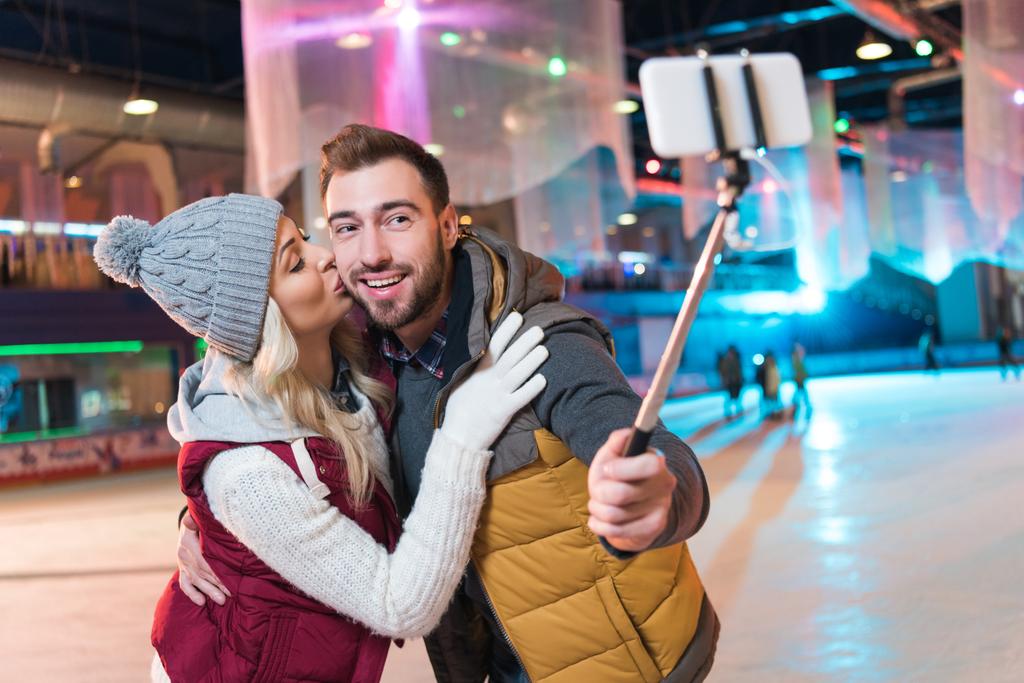 glückliches junges Paar macht Selfie mit Smartphone auf Eisbahn - Foto, Bild