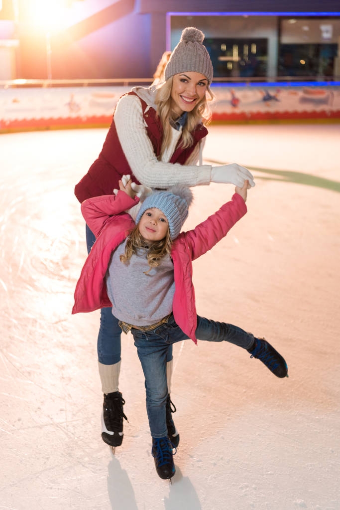 hermoso feliz padre e hija sonriendo a la cámara mientras patina en la pista de patinaje
 - Foto, Imagen
