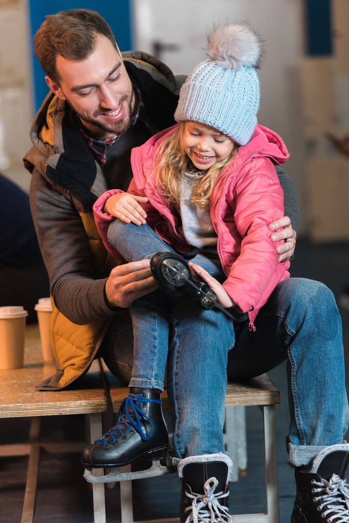 feliz padre e hija usando patines antes de patinar sobre hielo
 - Foto, Imagen