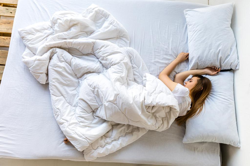Młoda kobieta, spanie w łóżku w rano, ogólny widok - Zdjęcie, obraz