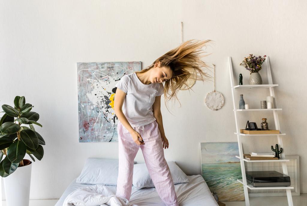 alegre joven en pijama bailando en la cama por la mañana en casa
 - Foto, Imagen