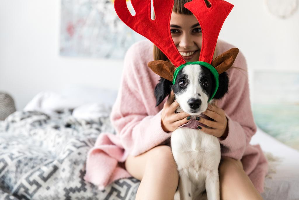 selective focus of smiling woman and cute little puppy with deer horns on head - Photo, Image