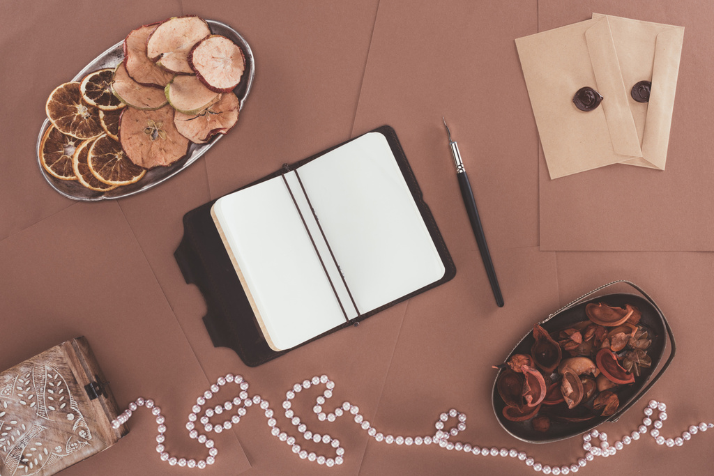 vista superior de notebook, caixa de jóias, frutas secas e envelopes sobre fundo de papel marrom
 - Foto, Imagem