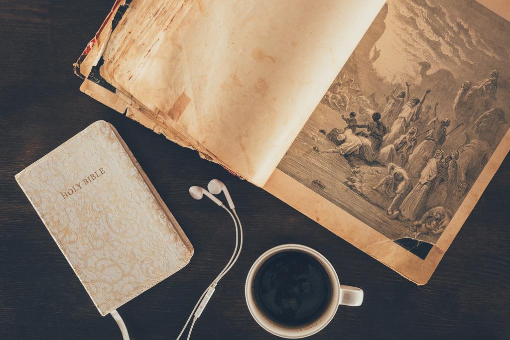 bovenaanzicht van de Heilige Bijbel, oortelefoons en cup op tafel - Foto, afbeelding