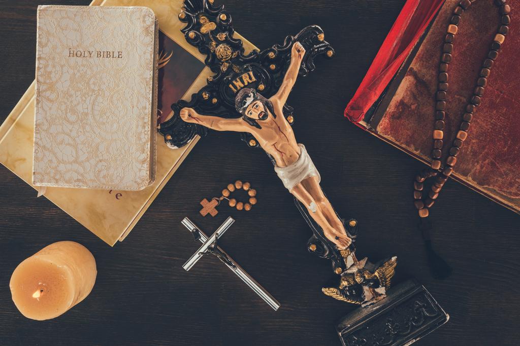 вид на крест с Иисусом и библиями на деревянном столе
 - Фото, изображение