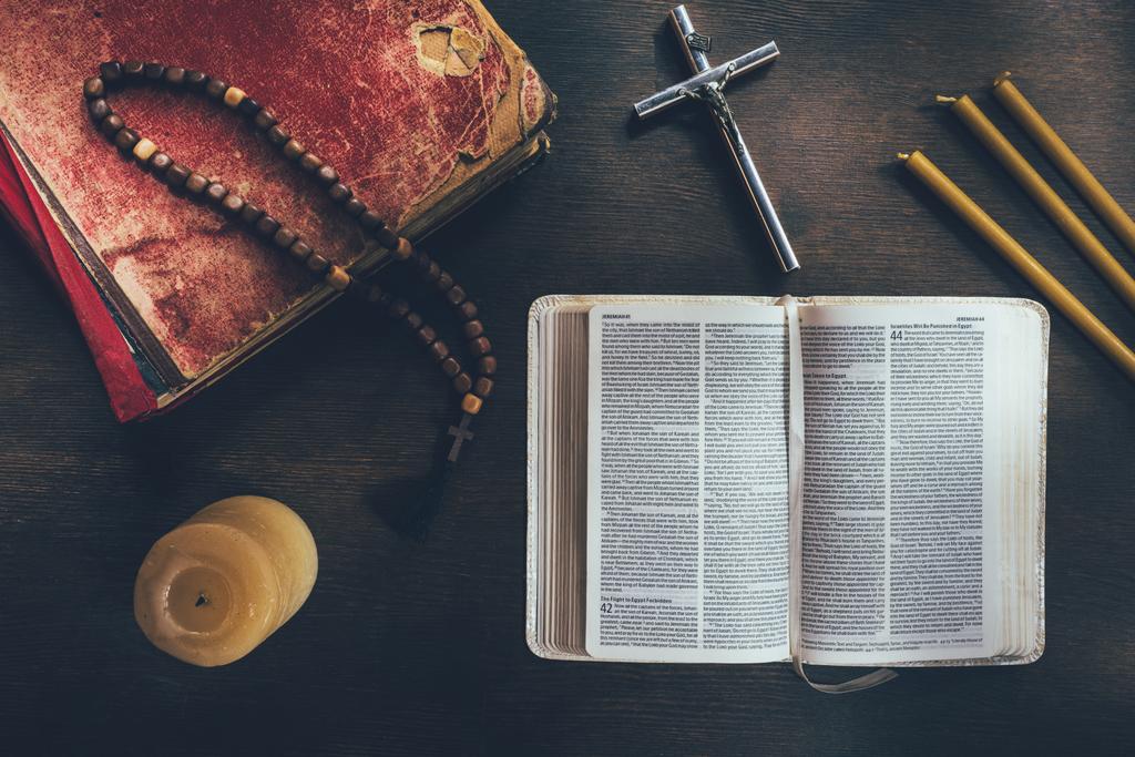 Ansicht der offenen Bibel mit Kreuz und Rosenkranz auf dem Tisch  - Foto, Bild