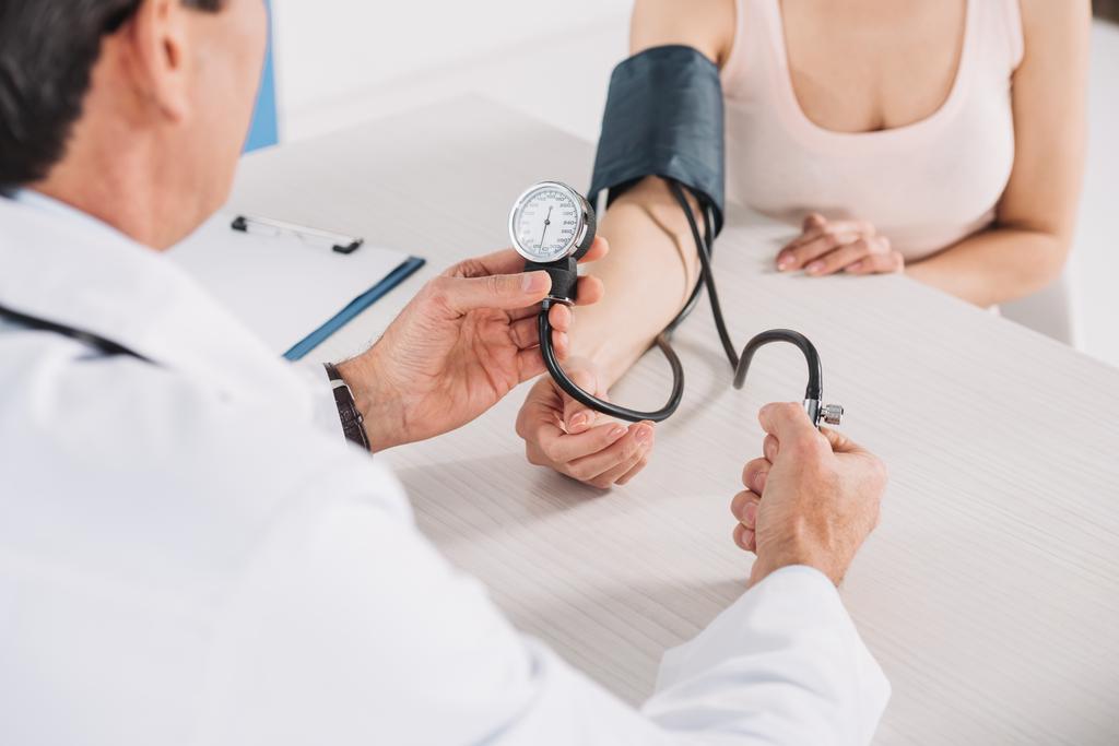 обрезанное изображение врача, измеряющего давление пациента
  - Фото, изображение