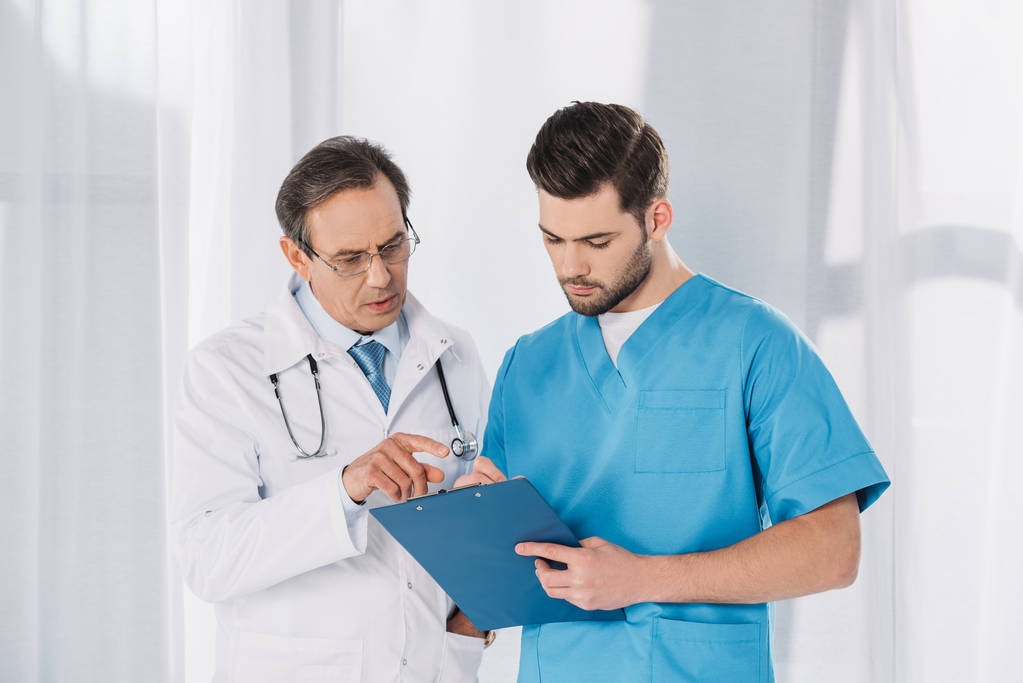male doctor and nurse looking at clipboard - Photo, Image