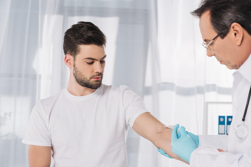 γιατρός λαμβάνοντας αίμα για τη δοκιμή του ασθενούς στα ιατρικά γάντια - Φωτογραφία, εικόνα