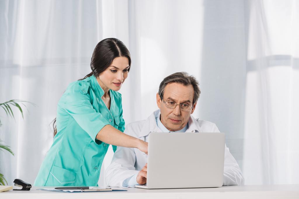 enfermeira mostrando algo no laptop para o médico
 - Foto, Imagem