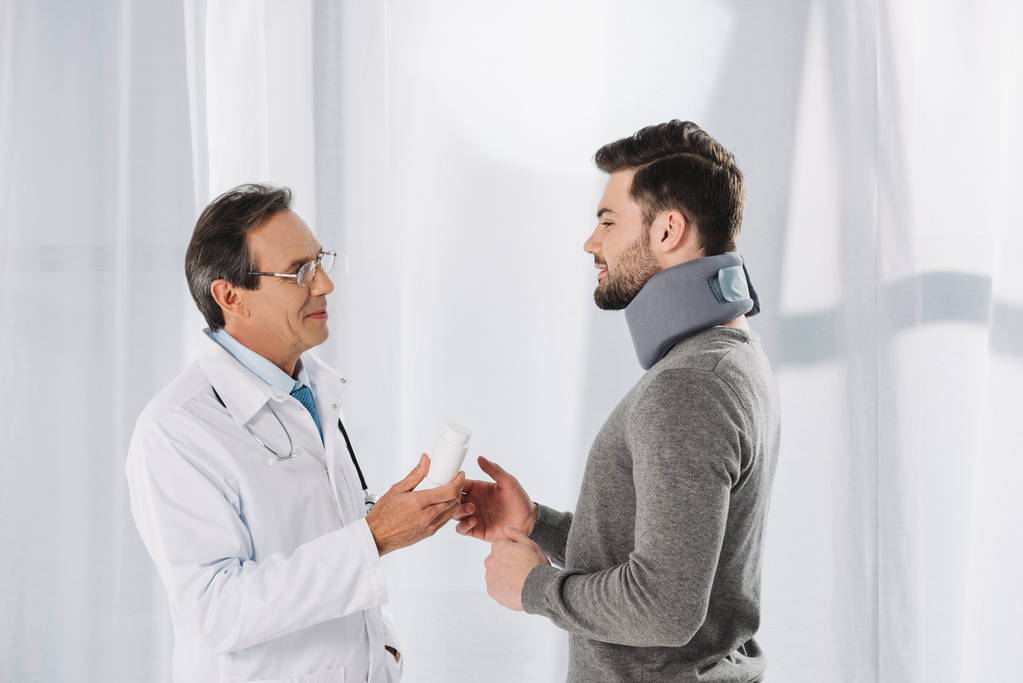 Arzt gibt Patientin im Nackenbereich Tabletten - Foto, Bild