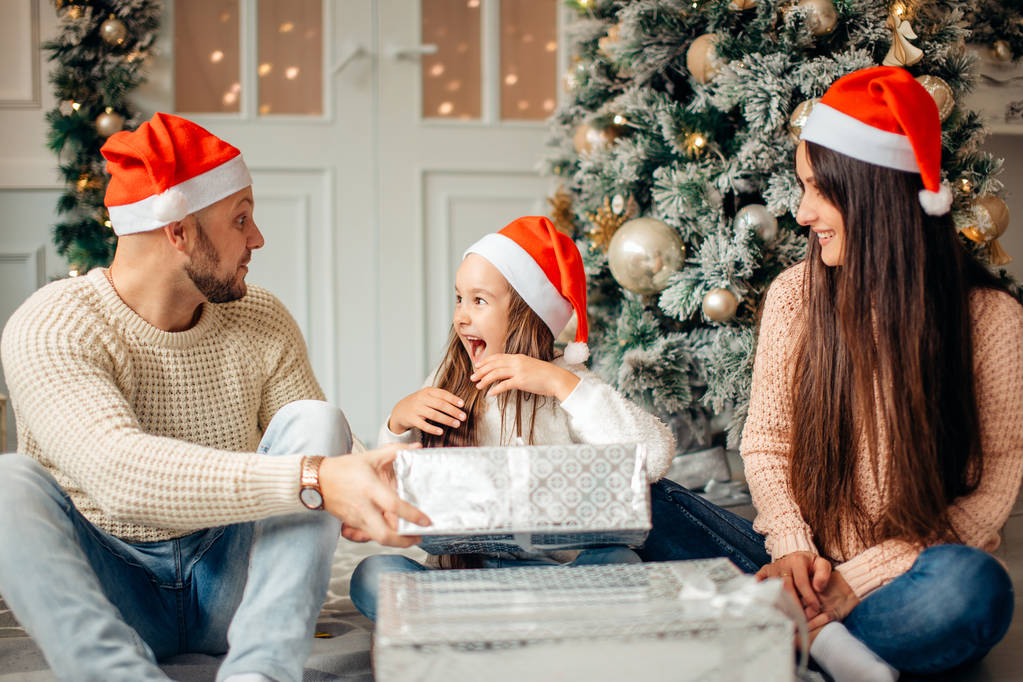 Menina surpreendida com presentes de Natal perto de uma árvore de Natal em casa
 - Foto, Imagem