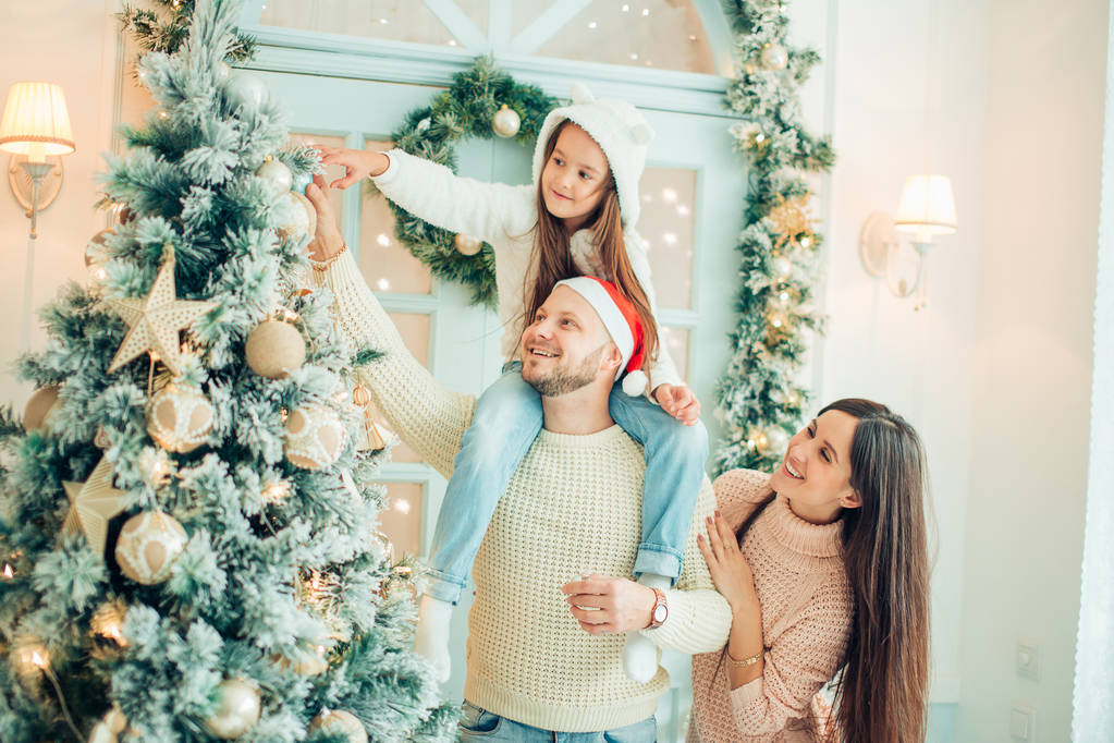 Gelukkig gezin versiert een kerstboom met boubles in de woonkamer - Foto, afbeelding