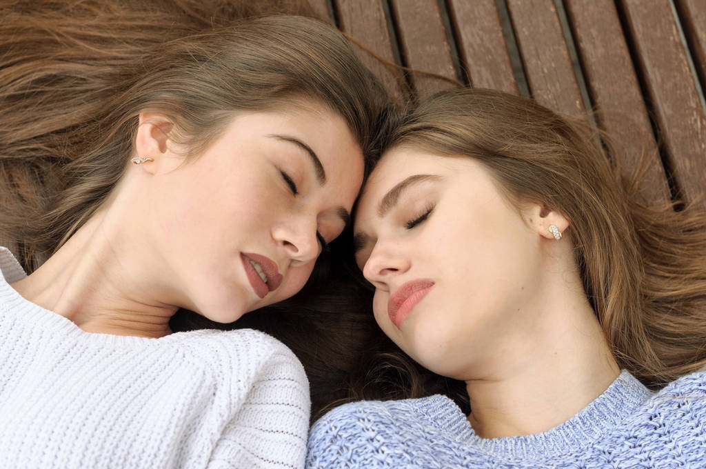 Dois amigos se deitam em um banco encostando a cabeça uns contra os outros
 - Foto, Imagem