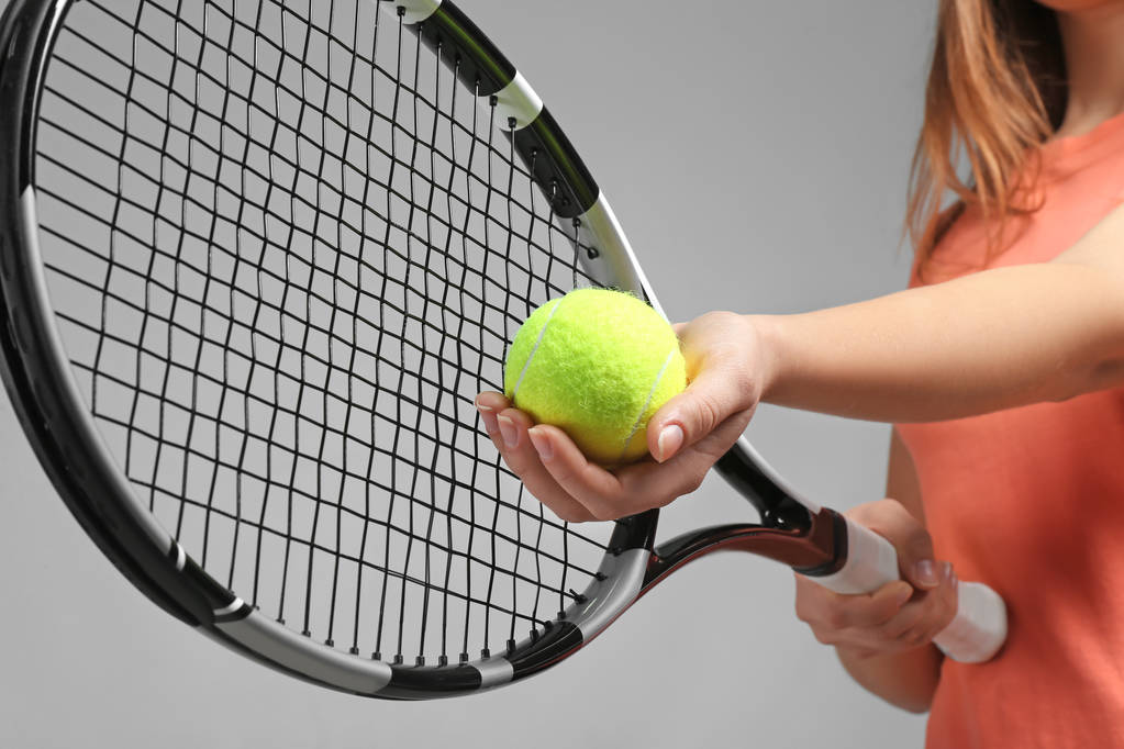 Жінка з тенісною ракеткою і м'ячем на сірому фоні
 - Фото, зображення