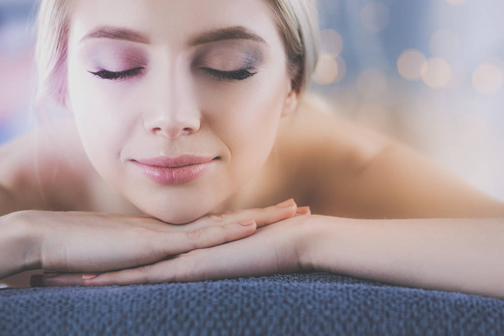 Mujer joven acostada en una mesa de masaje, relajándose con los ojos cerrados. Una mujer. Salón de spa
 - Foto, Imagen
