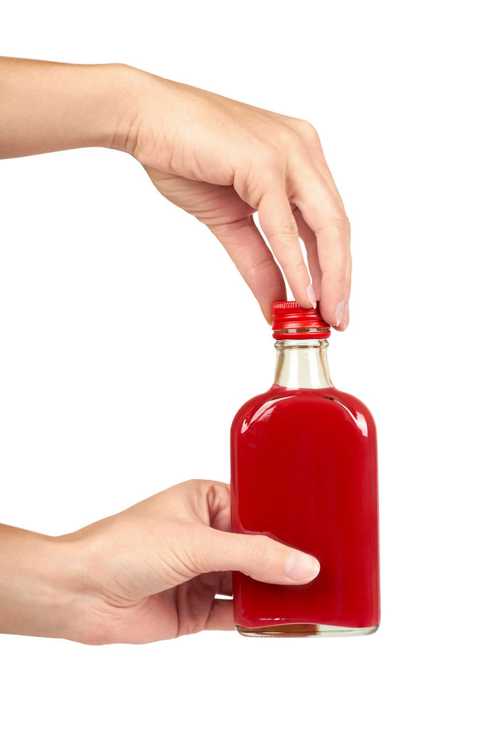 Butelka szklana z czerwonym nalewki w ręku na białym tle na białym tle. Problemy z alkoholem - Zdjęcie, obraz