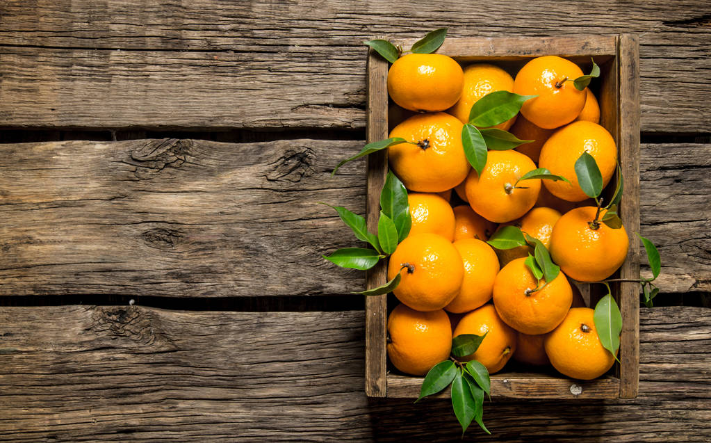 mandarines fraîches dans une vieille boîte avec des feuilles
.  - Photo, image