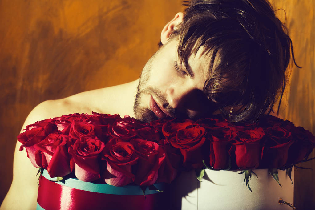 бородатий м'язистий чоловік з сексуальним тілом тримає червону коробку троянд
 - Фото, зображення