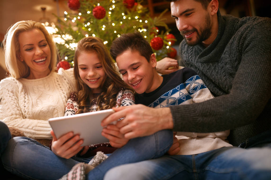 Οικογένεια μαζί για τα Χριστούγεννα που αναζητούν φωτογραφίες για tablet - Φωτογραφία, εικόνα