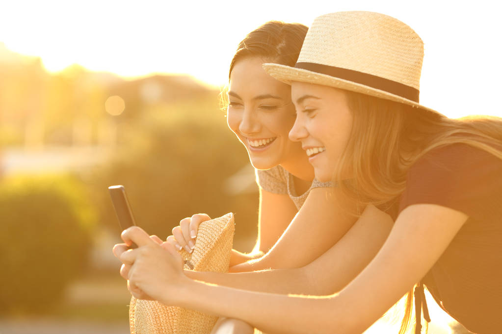 Kaksi ystävää katsomassa online-sisältöä auringonlaskun aikaan
 - Valokuva, kuva