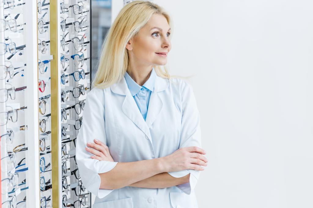 ophtalmologiste féminine debout dans l'optique avec des lunettes sur les étagères
 - Photo, image