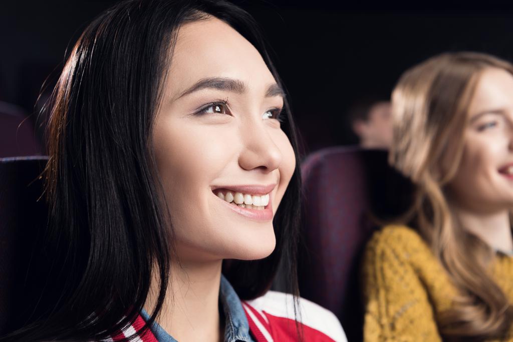 улыбающаяся азиатская девушка смотрит фильм в кинотеатре
 - Фото, изображение