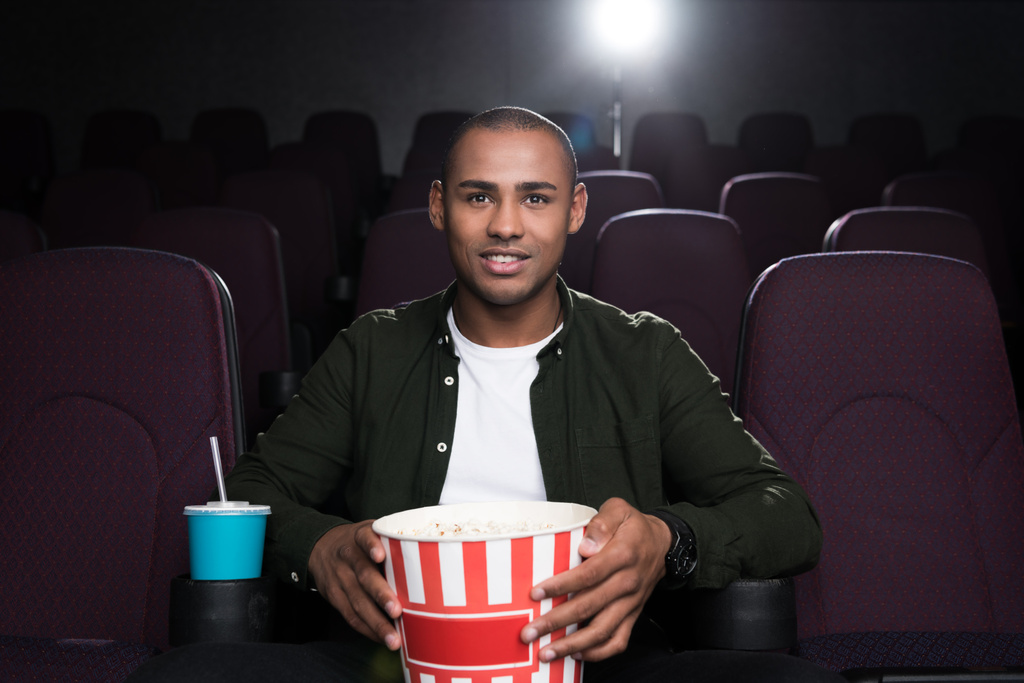 афроамериканський чоловік з попкорном і содовою дивитися фільм у кінотеатрі
 - Фото, зображення