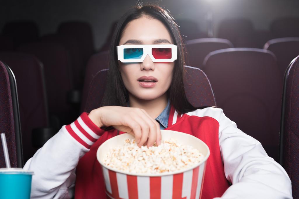young asian girl in 3d glasses with big basket of popcorn watching movie in cinema - Photo, Image