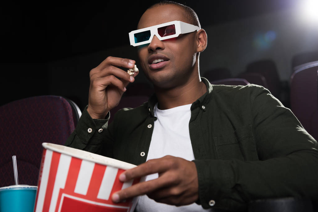 Američan Afričana muž v 3d brýlích jíst popcorn a sledování filmu v kině - Fotografie, Obrázek
