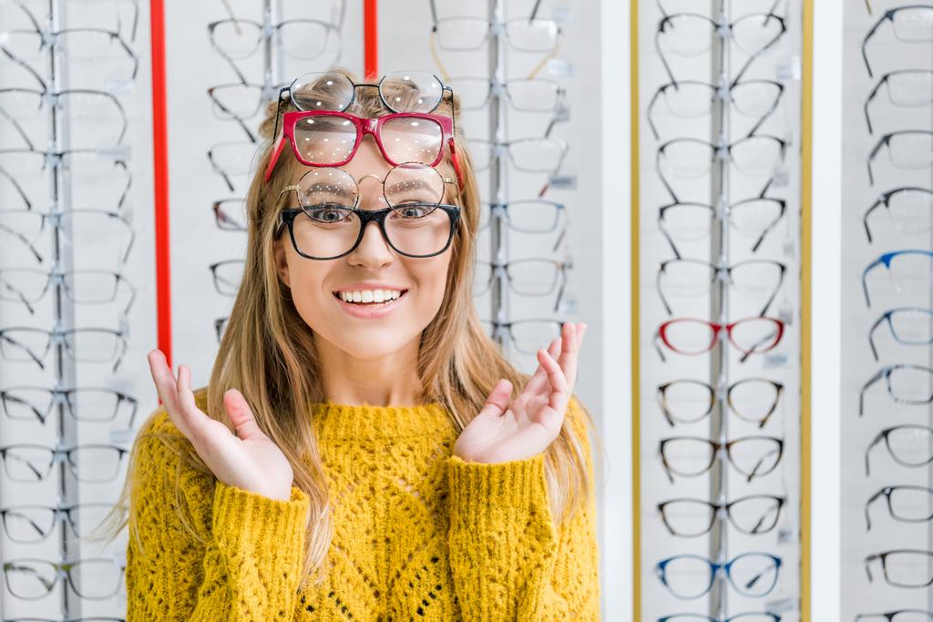 joven sorprendida chica elegir gafas graduadas en óptica
 - Foto, Imagen