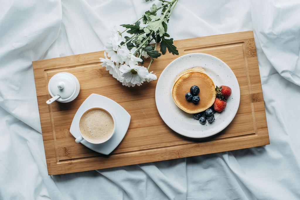 κάτοψη του πρωινό στο κρεβάτι με καφέ και νόστιμα τηγανίτες σε ξύλινη θήκη - Φωτογραφία, εικόνα