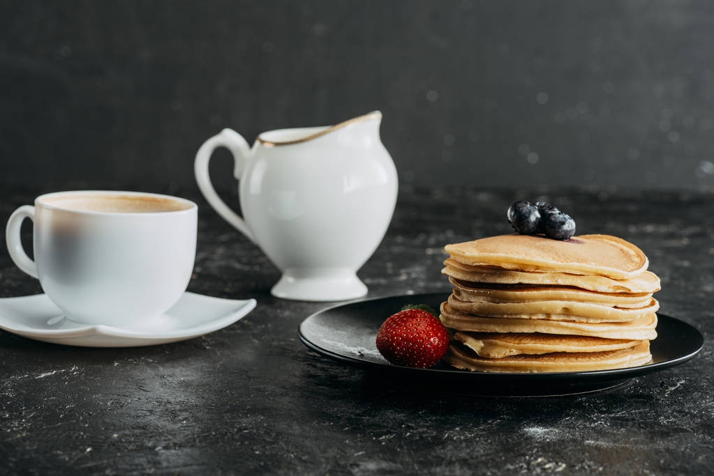 plaat van heerlijke gestapelde pannenkoeken met kopje koffie - Foto, afbeelding