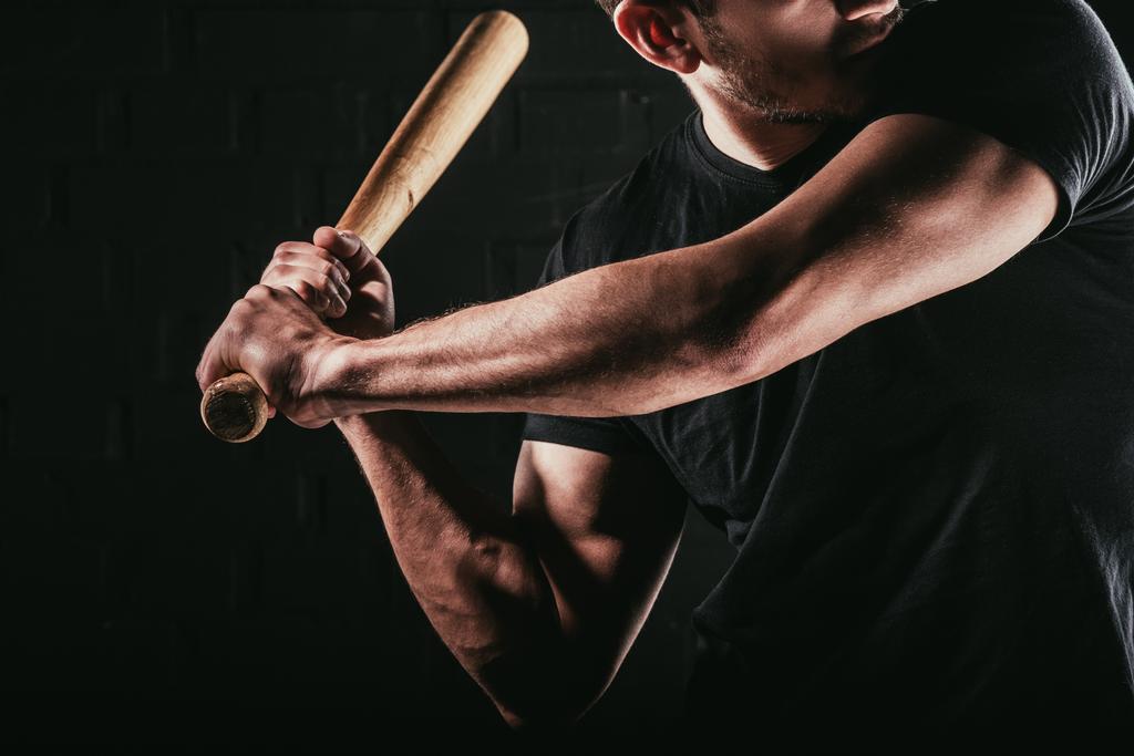 частичный взгляд молодого спортсмена, играющего в бейсбол с летучей мышью, изолированной на черном
  - Фото, изображение