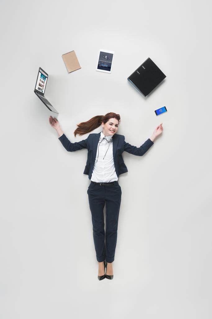 vue aérienne de femme d'affaires avec divers fournitures de bureau à l'aide d'un ordinateur portable isolé sur gris
 - Photo, image