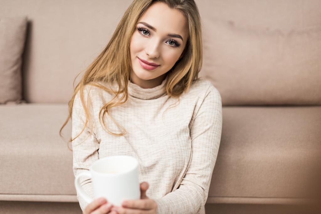 красива молода жінка в теплому светрі з чашкою гарячого напою вдома
 - Фото, зображення
