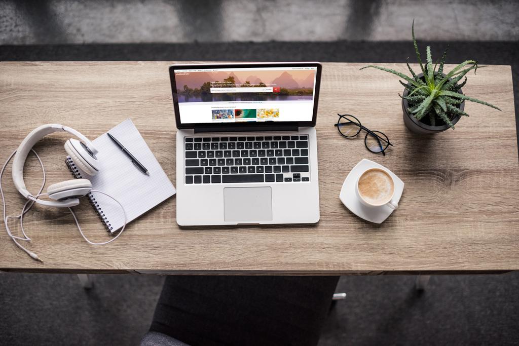 Draufsicht auf Laptop am modernen Arbeitsplatz mit Shutterstock-Homepage-Website auf dem Bildschirm - Foto, Bild
