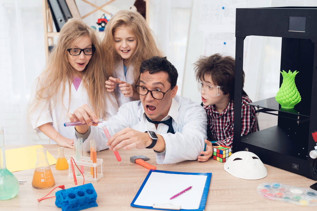 Niños con batas blancas hacen experimentos químicos durante la lección en el aula
. - Foto, Imagen